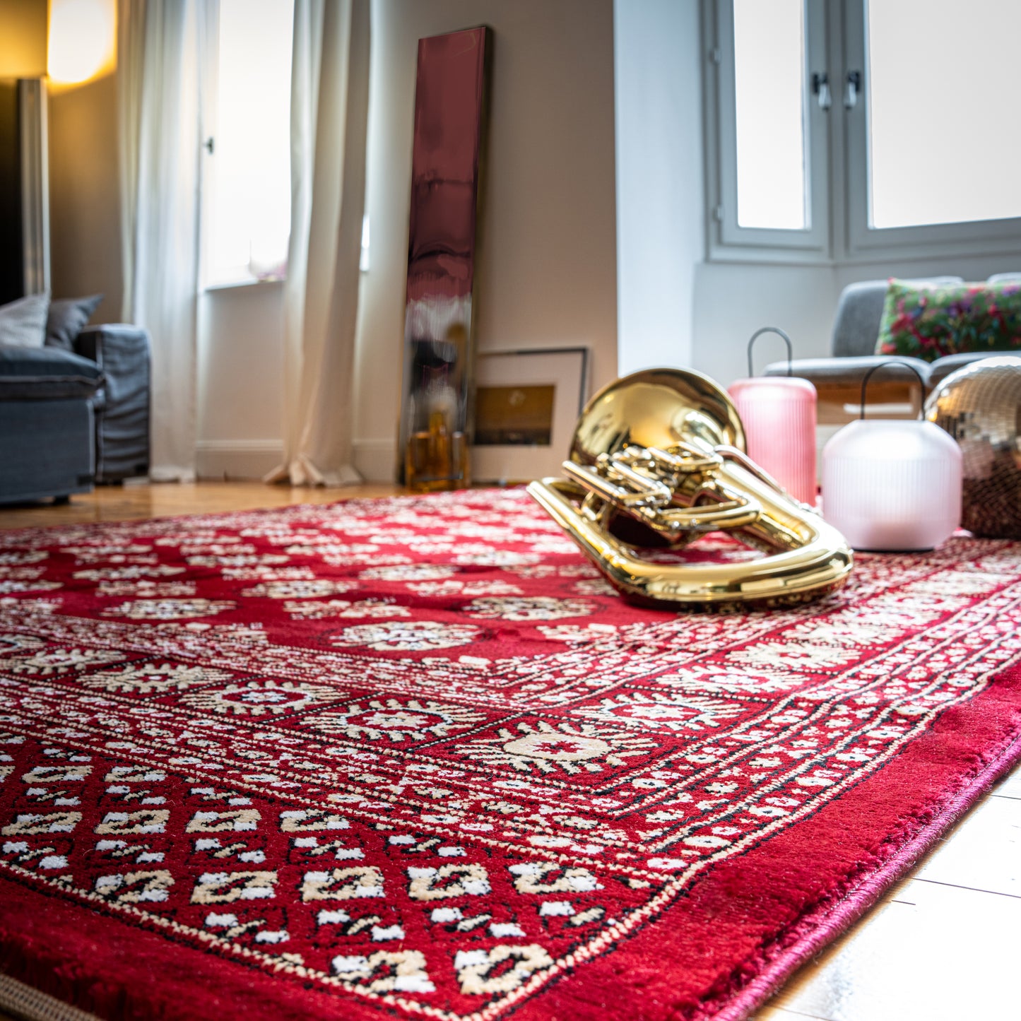 Rood handgemaakt vloerkleed in een creatieve woonkamer met muziekinstrumenten en natuurlijk licht
