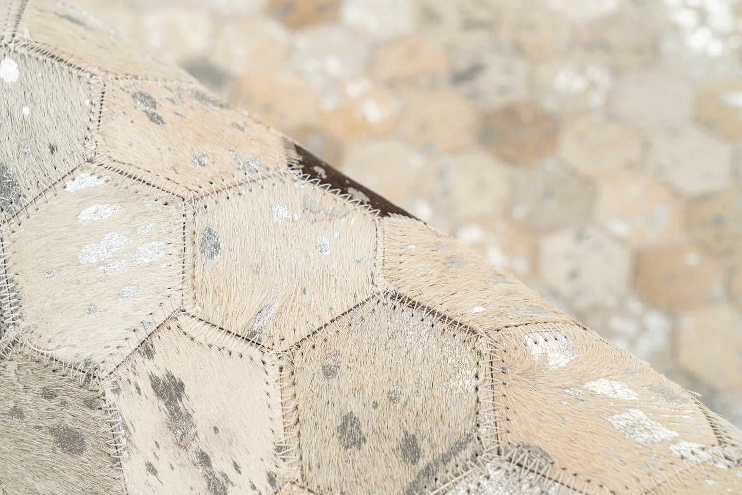 Close-up van het hexagon patroon van het leren vloerkleed Lanvin 1026 met goud- en zilveraccenten.