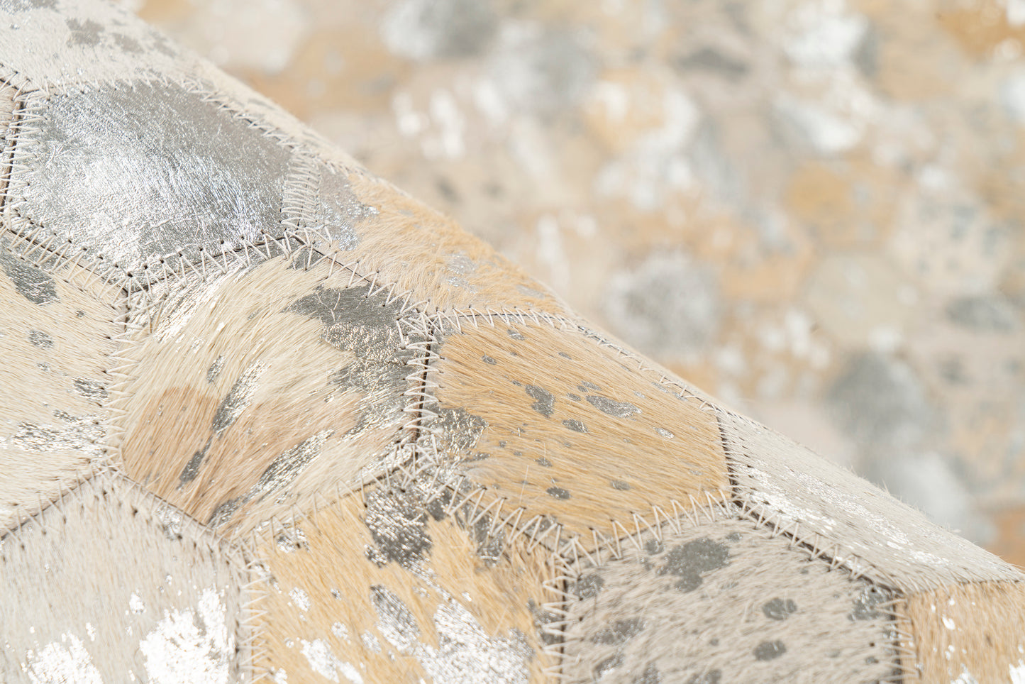 Detailopname van het LaleeAvenue vloerkleed Lanvin met hexagon-patroon in goud- en zilvertinten, handgemaakt van 100% leer.