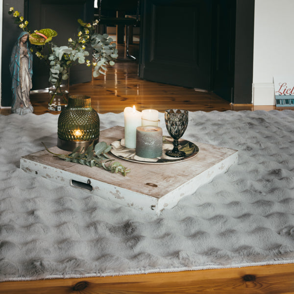 Sfeervolle setting met zilvergrijs My Aspen vloerkleed, decoratief gestyled met kaarsen en vaas