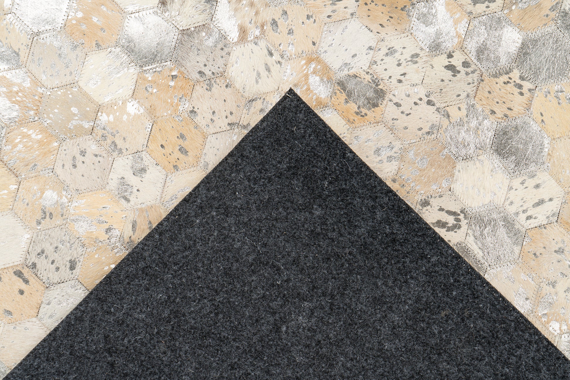 Achterkant van het LaleeAvenue vloerkleed Lanvin, zwart viltmateriaal met zichtbare handgemaakte hexagon-leren bovenkant in goud- en zilvertinten.