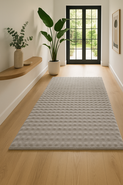 Luxe vloerkleed in zilvergrijs, geplaatst in een moderne, lichte gang met minimalistische inrichting en bovenaanzicht.